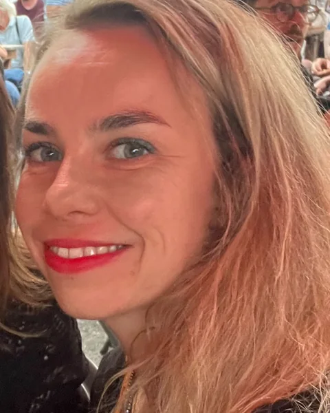 Portret van Bo Heylen, lachend, met blond haar en rode lippenstift.